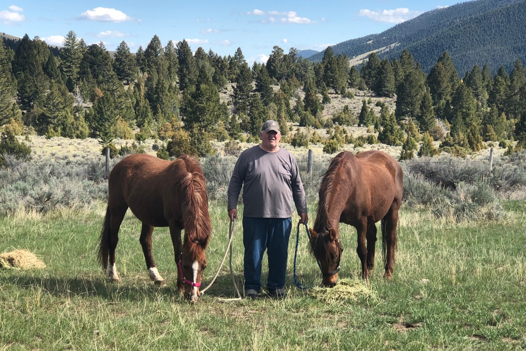 man holding reins of 2 horses