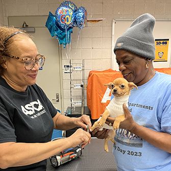 A woman holding her dog while ASPCA staff gives it a vaccine
